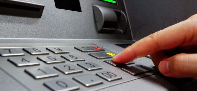 a hand is pressing a button on an atm machine.