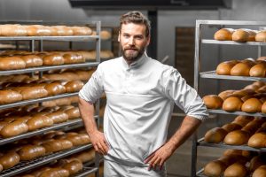 a man standing in front of a rack of bread.